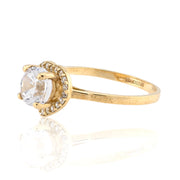 Gold ring with a clear gemstone on a white background