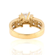 Yellow gold engagement ring featuring a round brilliant cut center stone in a four-prong setting with a wide channel-set diamond band.