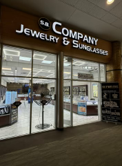 Storefront of a jewelry and sunglasses shop with large glass windows.