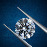 Diamond held between two tweezers against a blue background