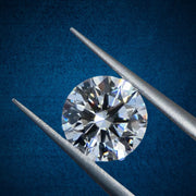 Diamond held between two tweezers against a blue background